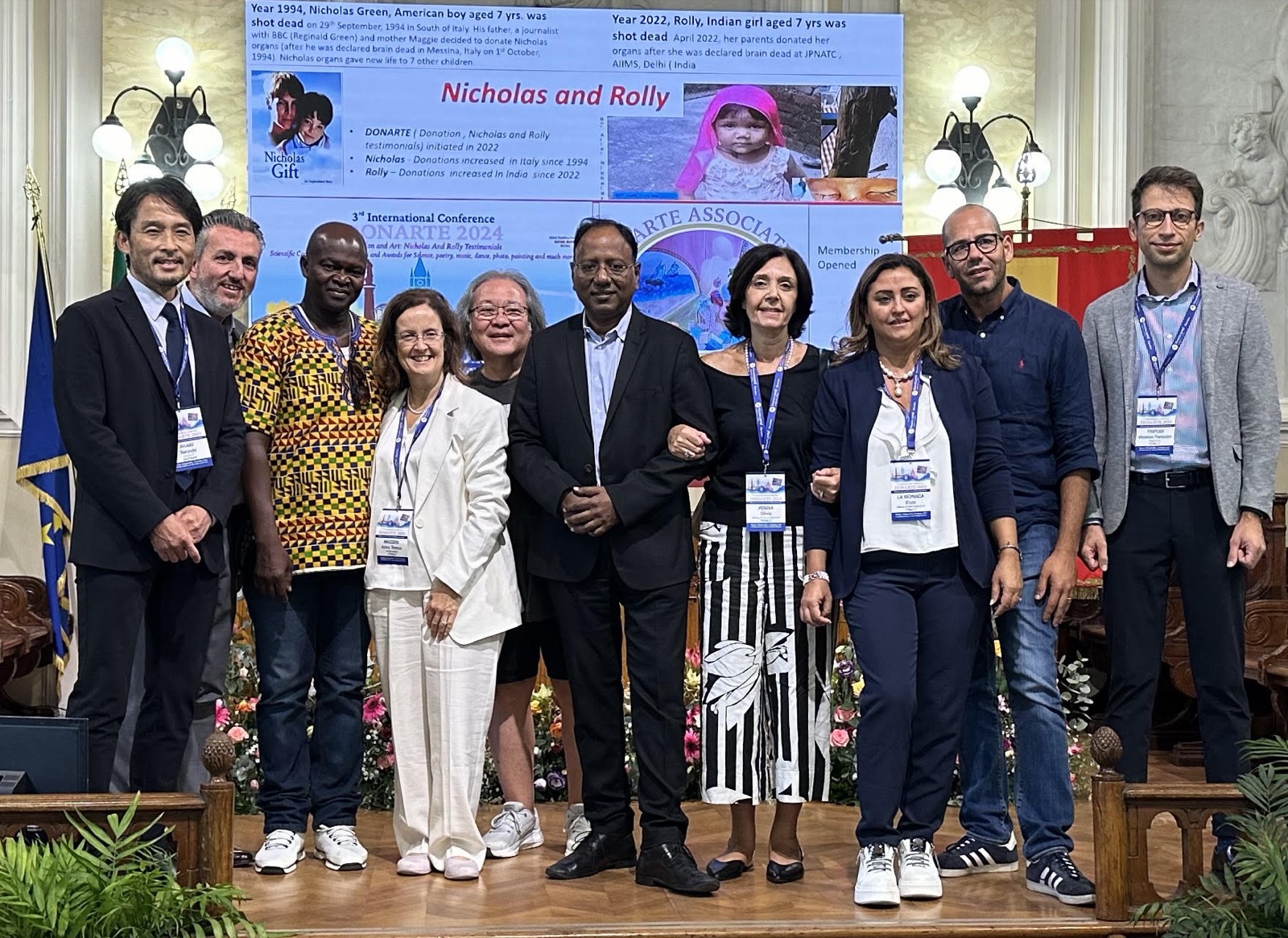 I soci fondatori dell'associazione sul palco del terzo congresso DONARTE, davanti al pannello che racconta le storie di Nicholas e Rolly